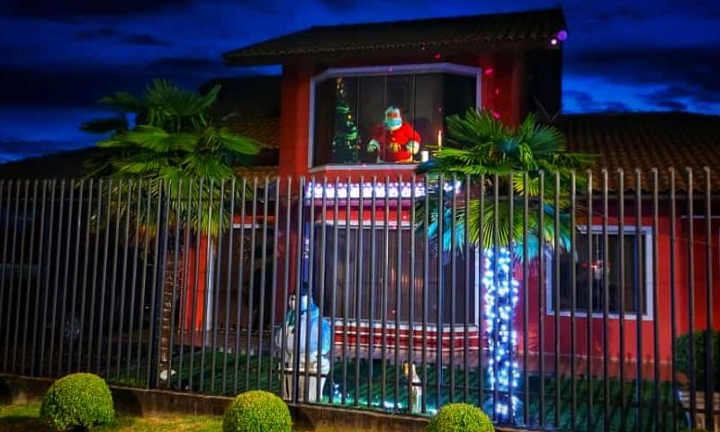 Papai Noel deixa os presentes na árvore, espia e manda até tchau